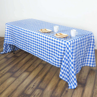 Blue and white checkered tablecloth draped over a table with plates and cups.
