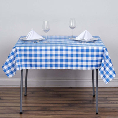 Blue and white checkered tablecloth on a dining table with glassware and napkins.