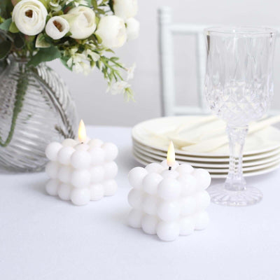 White bubble candles on a dining table with flowers and glassware.