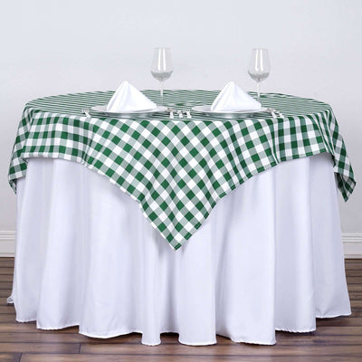 Green and white checkered tablecloth draped over a round table with napkins and glasses.