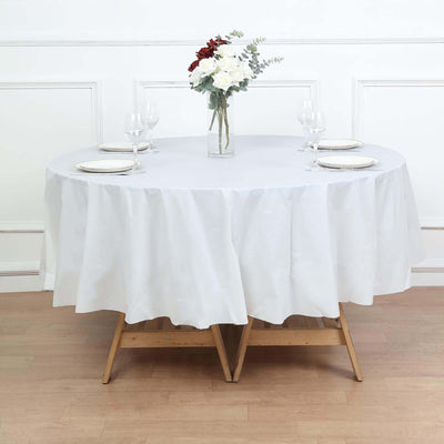 Round dining table set with white tablecloth and floral centerpiece.