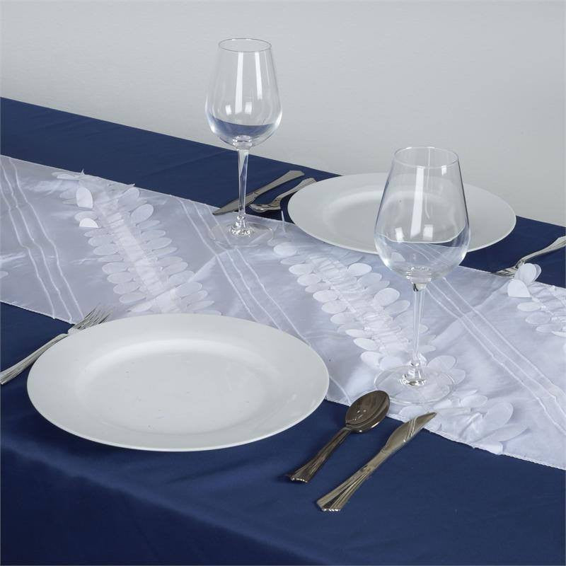 Elegant table setting with white plates and wine glasses on a blue tablecloth.