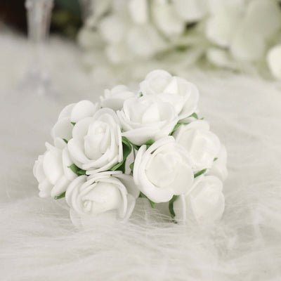White floral arrangement of artificial roses on soft textured surface.