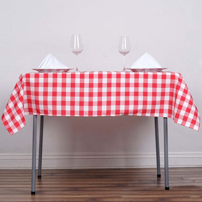 Red and white gingham tablecloth on a dining table with glasses and plates.