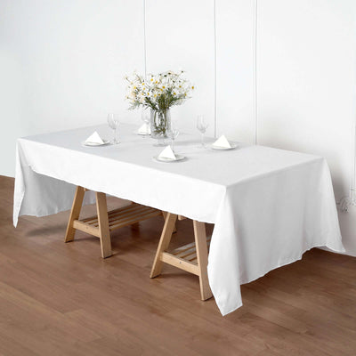 White dining table set with flowers and glassware, styled for an elegant meal.