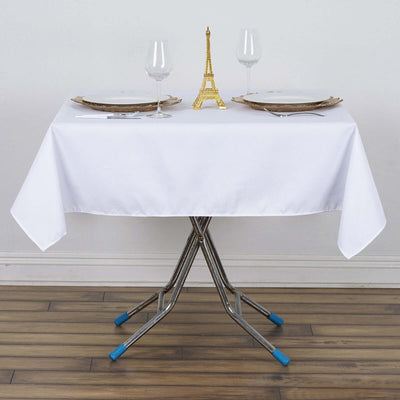 Elegant white table setup with glassware and Eiffel Tower centerpiece.