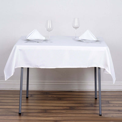 Elegant dining table set with white tablecloth, plates, and glassware.