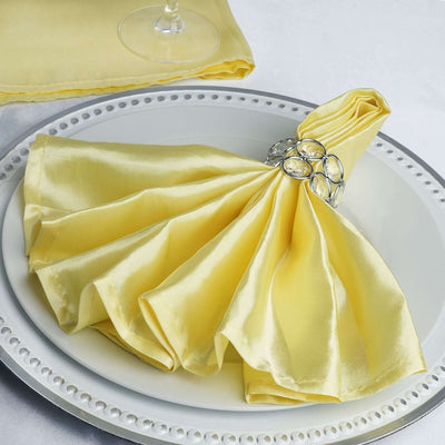 Yellow satin napkin elegantly arranged on a plate with a decorative napkin ring.
