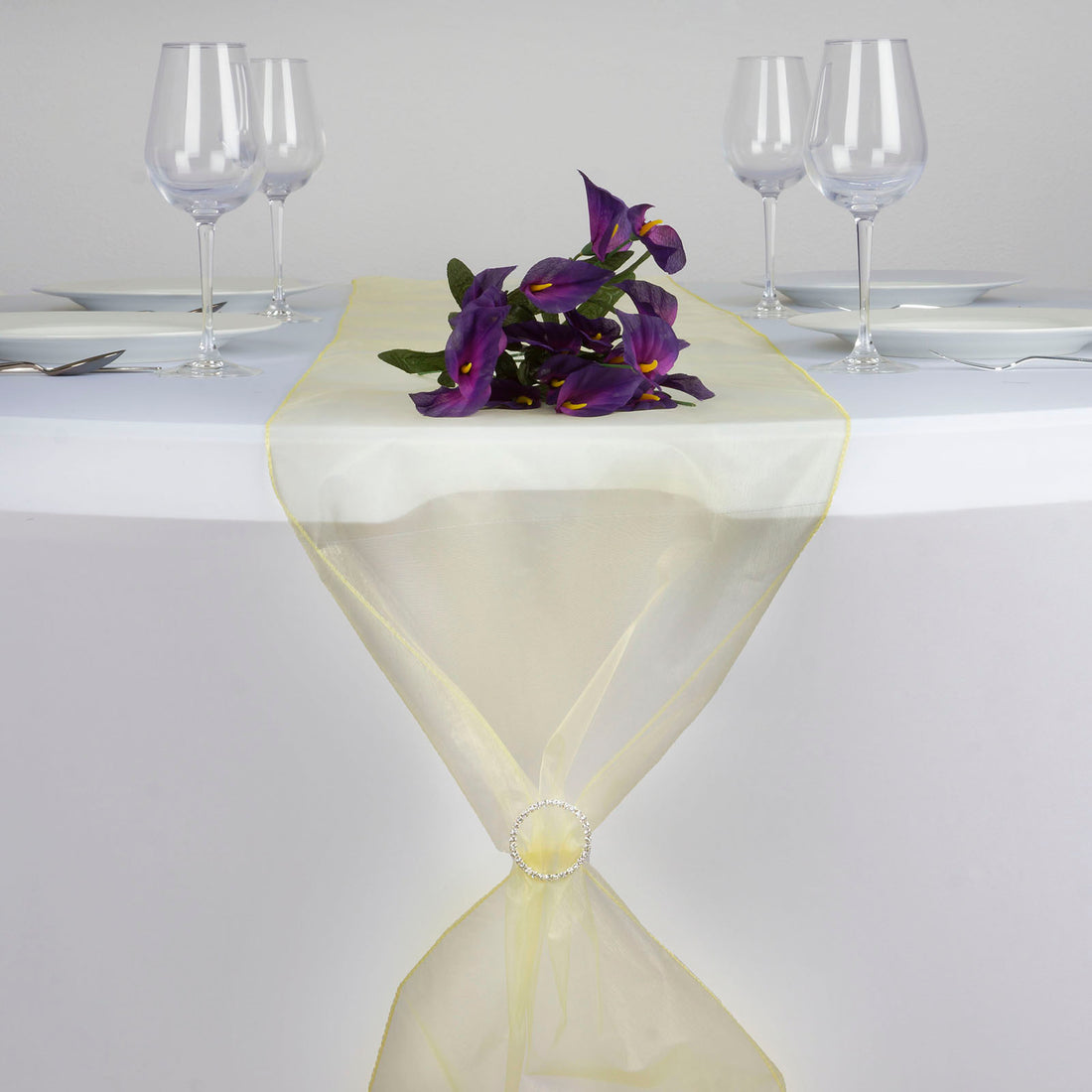 Elegant yellow table runner with purple flowers on a dining table setting. #whtbkgd