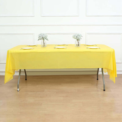 Yellow tablecloth draped over a table set with flowers and plates in a staged dining scene.
