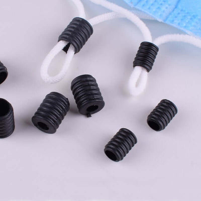 Black mask ear strap adjusters on a white background.