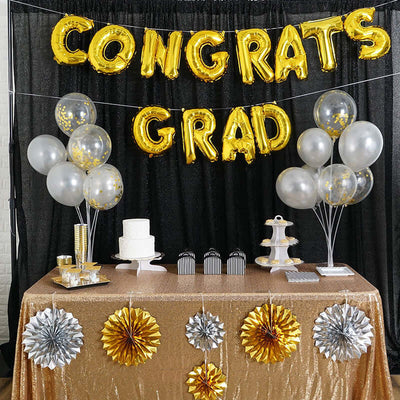 Gold "Congrats Grad" balloons with decorations on a festive table.